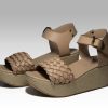 Plataformas beige de mujer con trenzas en empeine y talon con herraje, vista lateral.