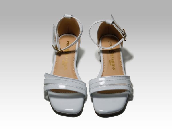 Sandalias blancas de niñas con tacón, con tiritas en el empeine y talón con herraje, vista frontal.