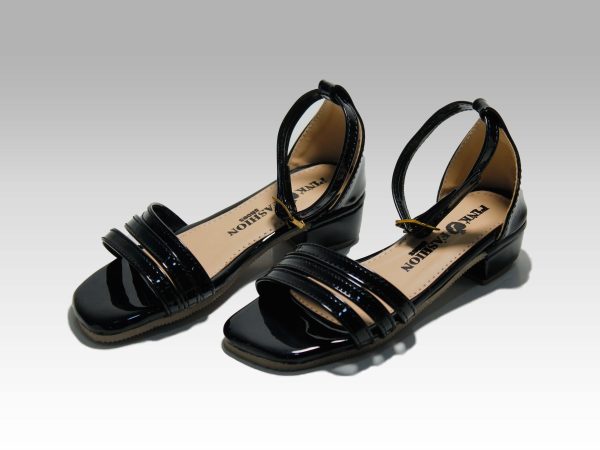 Sandalias negras de niñas con tacón, con tiritas en el empeine y talón con herraje, vista lateral.