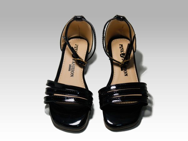 Sandalias negras de niñas con tacón, con tiritas en el empeine y talón con herraje, vista frontal.